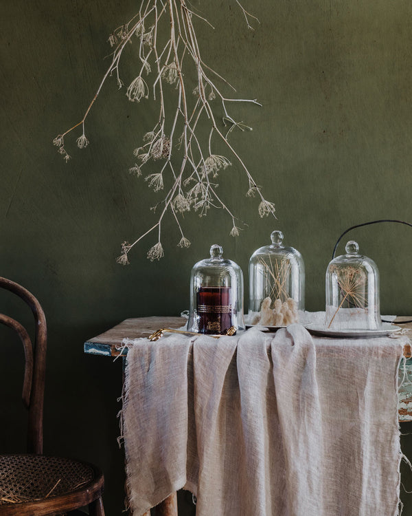 A vintage table setting featuring glass cloches and candle scissors on a linen table cloth
