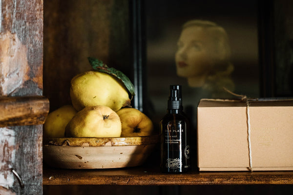 Southern Wild Co Our Place Room Mist displayed beside fresh quinces in a ceramic bowl and a kraft gift box. Set on a rustic wooden shelf, this styled image evokes Australian-made natural home fragrance, memory, and scent-inspired gifting.