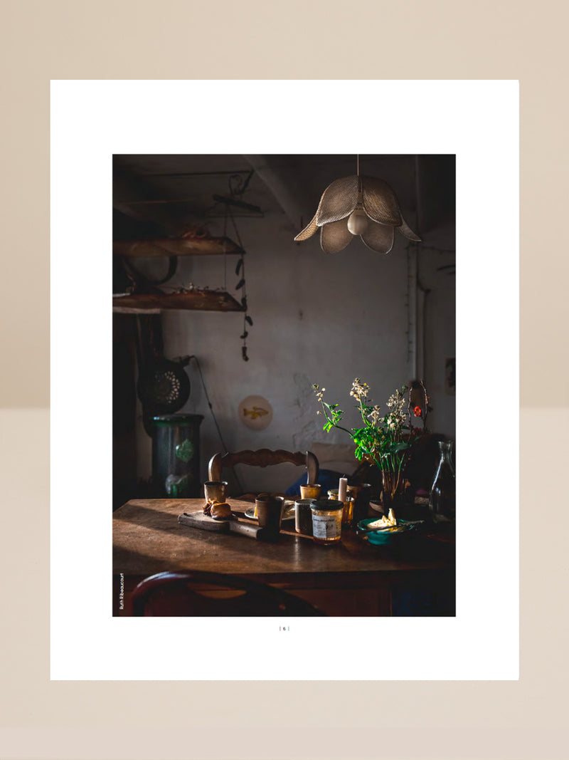 Dining area with wooden table, plants, and hanging light fixture.