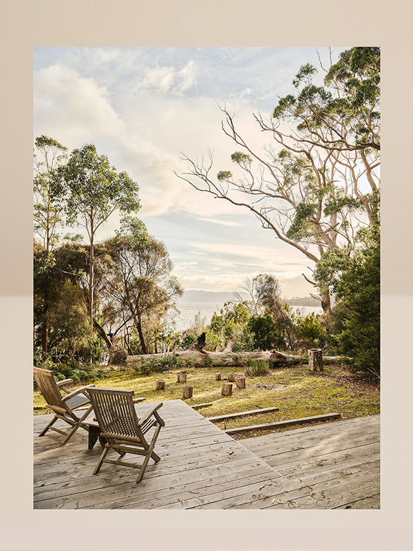 Wooden deck with chairs overlooking a scenic landscape with trees and mountains.