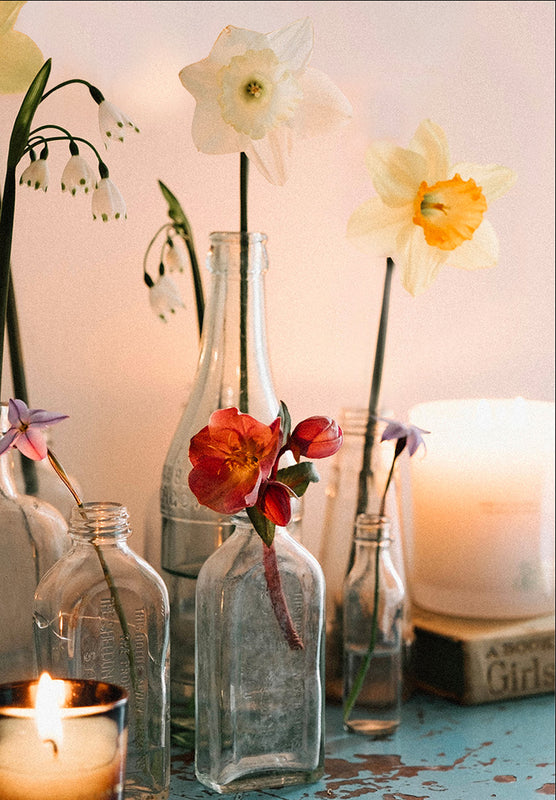 Daffodils, snowdrops and garden flowers displayed in vintage glass bottles