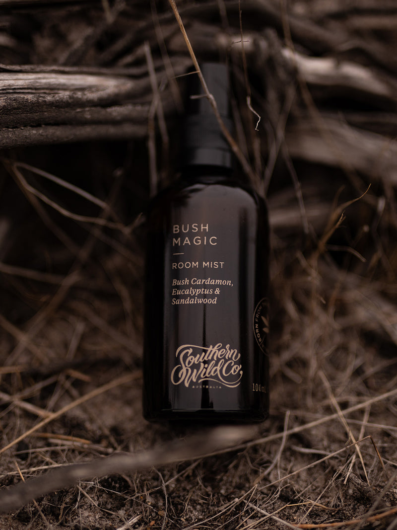 Bush Magic Room Mist nestled in dry bush grasses and weathered wood, evoking the earthy elegance of eucalyptus, bush cardamom and sandalwood.
