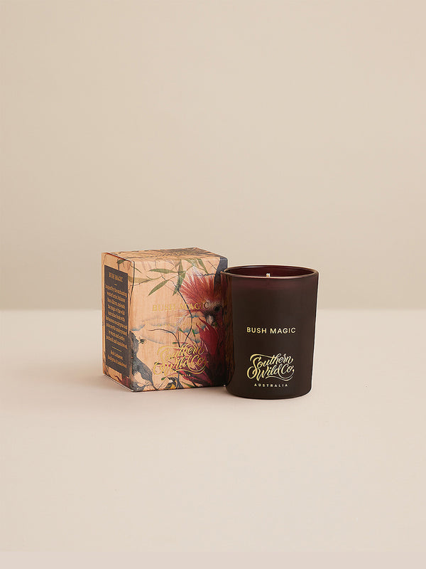 Studio product shot of the Bush Magic votive candle with matching illustrated box, featuring native flora artwork and gold-foil branding.