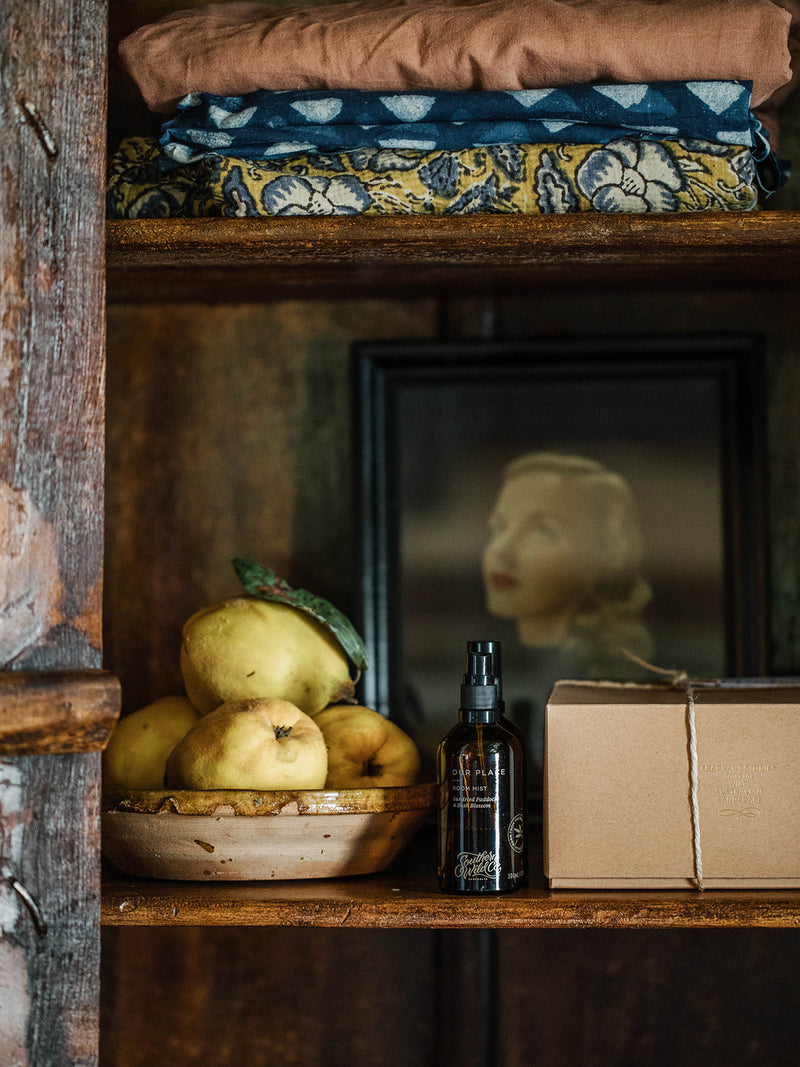 Our Place Room Mist by Southern Wild Co nestled in a timber cabinet with quinces, vintage linens, and heirloom details – natural Australian linen and room spray with nostalgic bush scent.