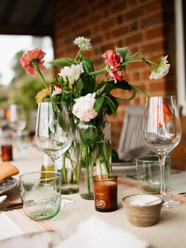 Our Place votive candle by Southern Wild Co styled on a garden table with fresh flowers, glassware, and linen – Australian made candle for outdoor entertaining and slow gatherings.