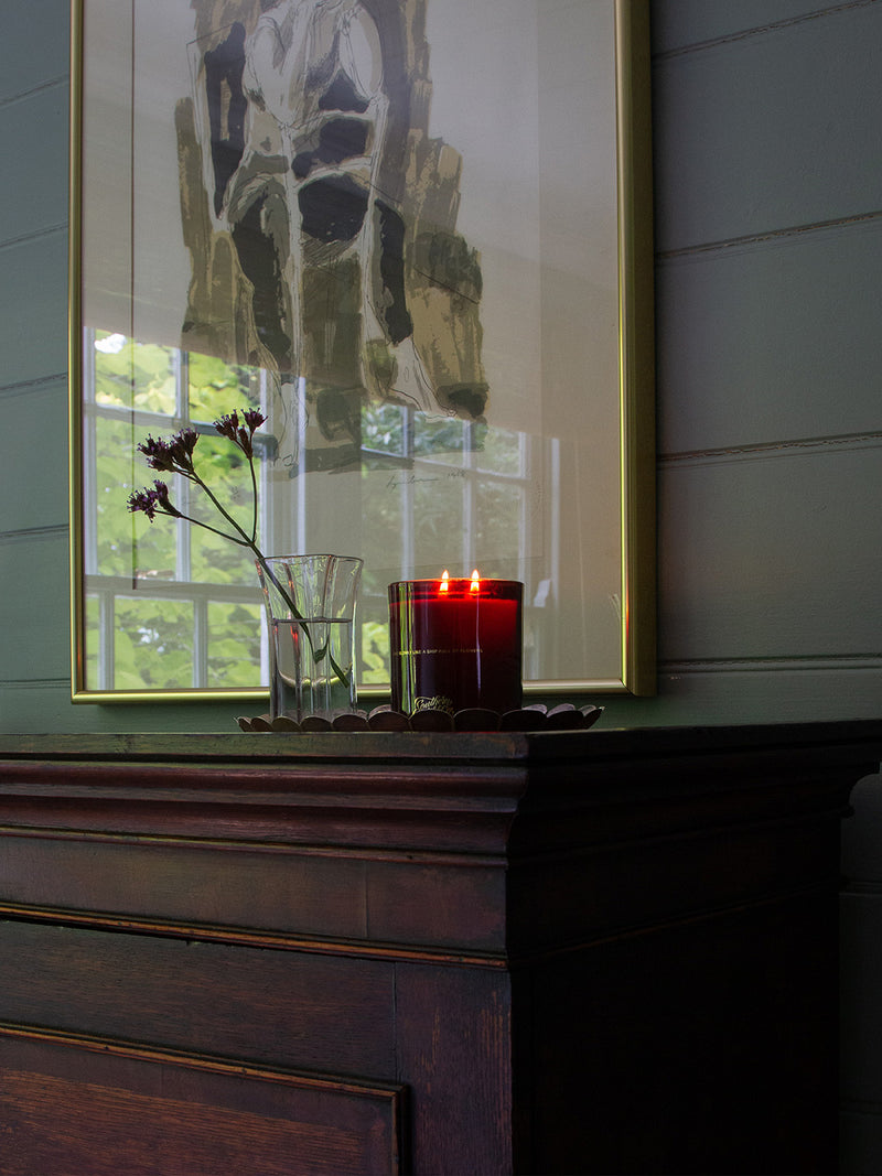 Sirens candle flickering on an antique timber mantel beneath modern abstract art – Southern Wild Co’s signature scent in a calm, collected space.