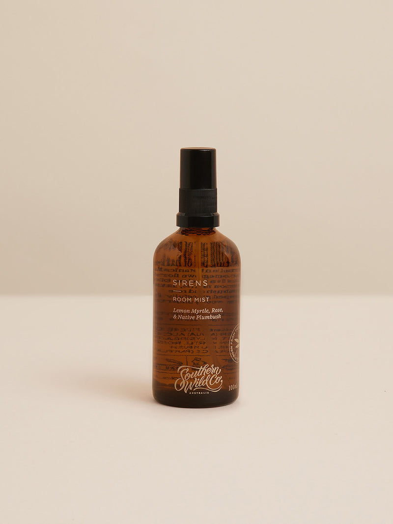 Amber glass bottle of Sirens Room Mist – featuring Lemon Myrtle, Rose and Native Plumbush – against a soft, neutral backdrop.