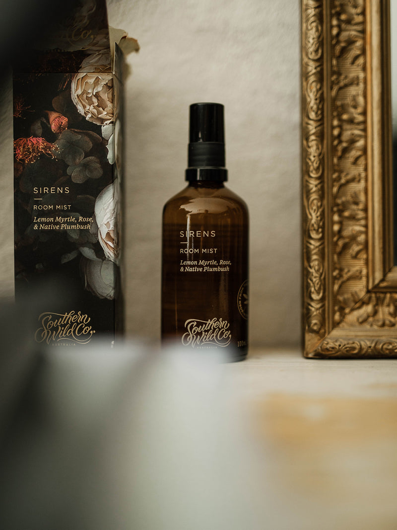 Sirens Room Mist and packaging leaning against a gilded vintage frame, capturing the interplay of scent, art and quiet ritual.