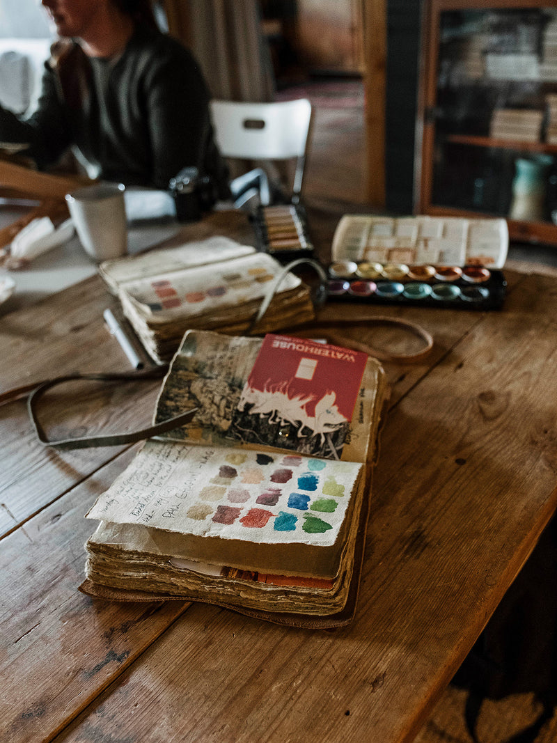 Open southern Wild co sketchbook with watercolor paint swatches on a wooden table
