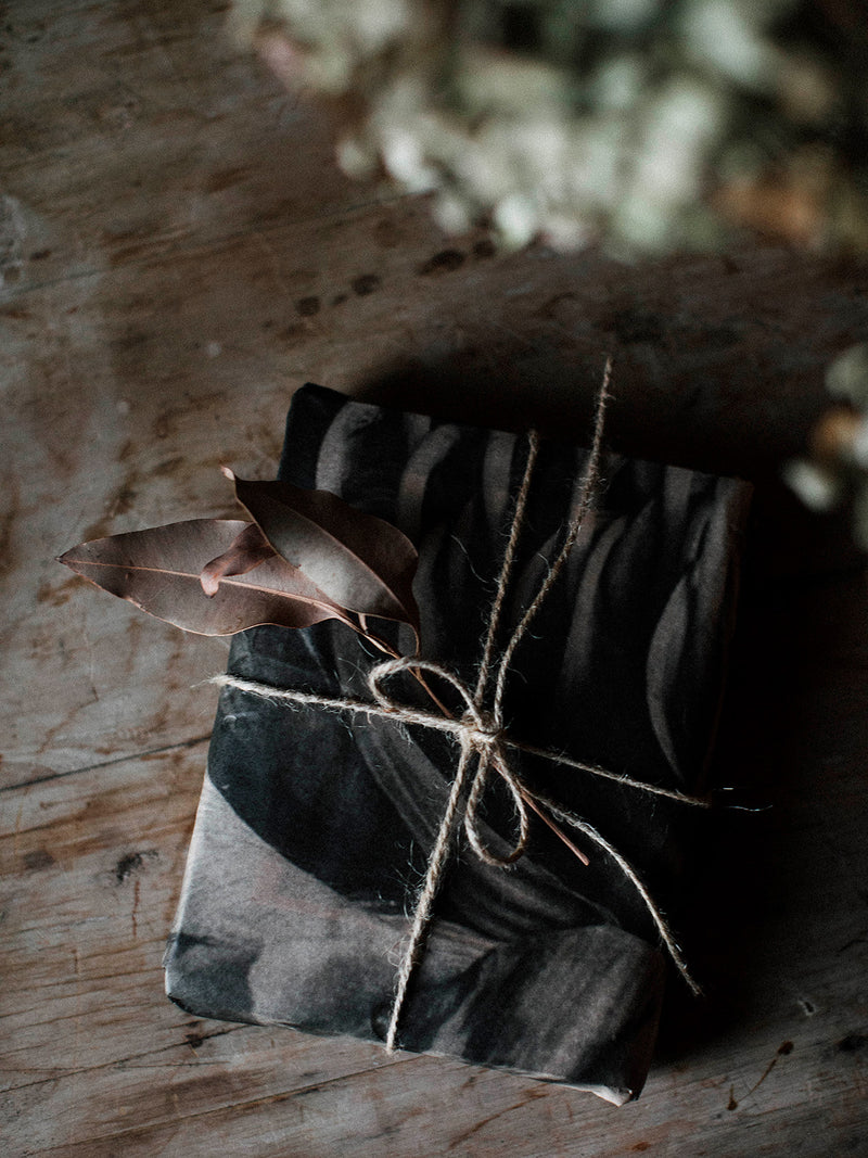Darkly wrapped gift with string on a rustic wooden surface
