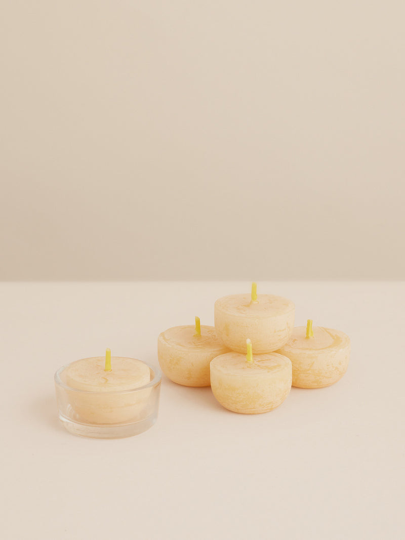 Natural beeswax tealight candles with yellow wicks, including one in a clear glass holder – handcrafted by Southern Wild Co.