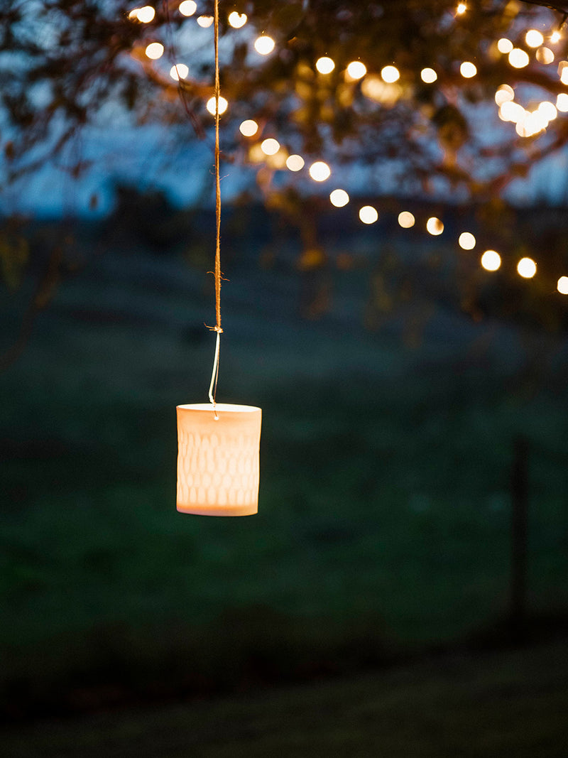 Hanging candle lantern with fairy lights in the background
