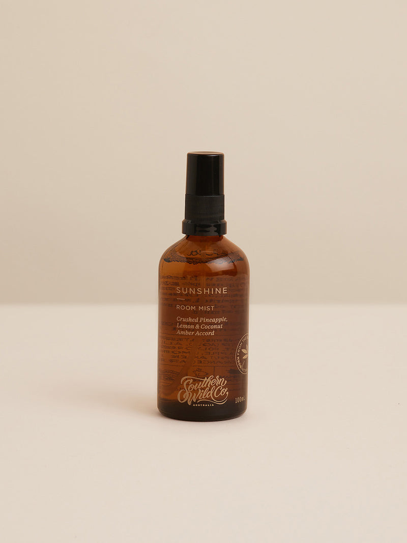 Studio-style image of Sunshine Room Mist — a 100ml amber glass bottle with notes of crushed pineapple, lemon, coconut and warm amber accord.
