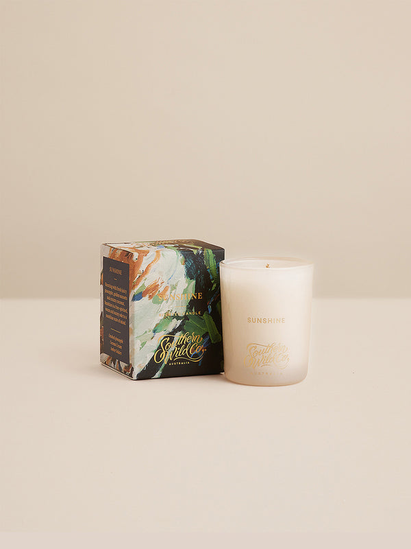 Studio-style image of the Sunshine votive candle beside its painterly box — a coastal-inspired gift of scent and light from Southern Wild Co.