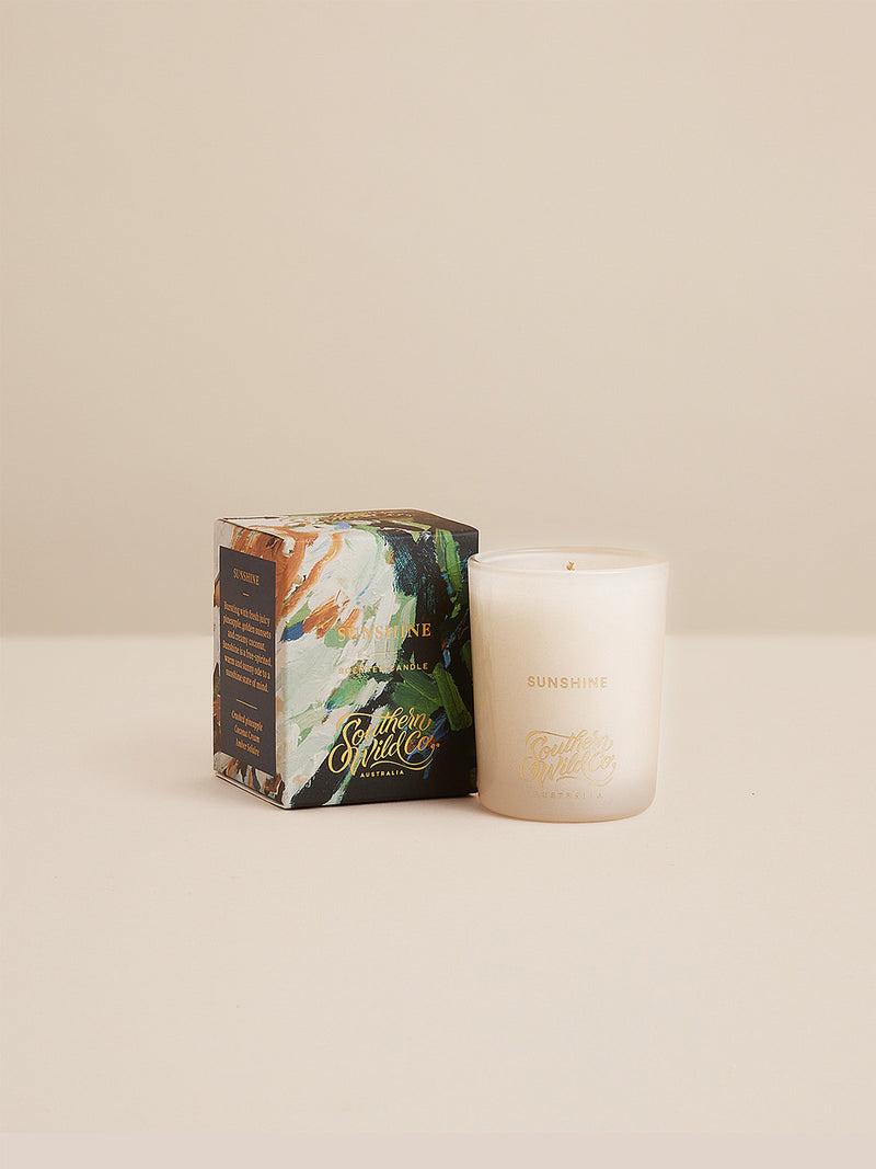 Studio-style image of the Sunshine votive candle beside its painterly box — a coastal-inspired gift of scent and light from Southern Wild Co.